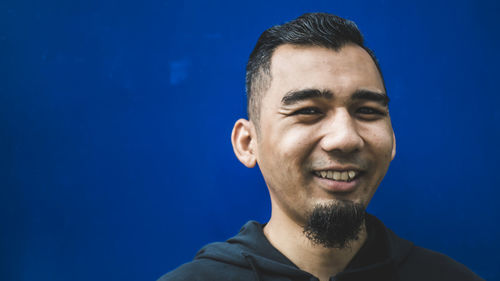 Portrait of young man against blue background