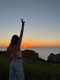 Rear view of woman standing on mountain against sky during sunset