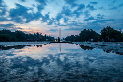 Reflection of washington monument in puddle against sky