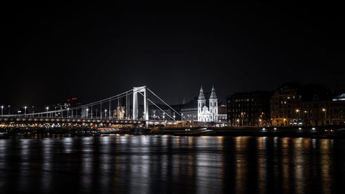 Illuminated bridge over river at night