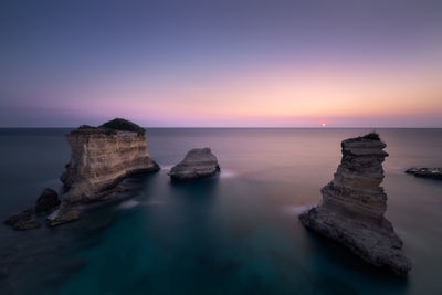 Scenic view of rocks in sea against sky during sunset