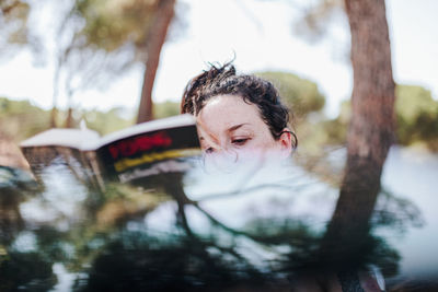 Portrait of woman with reflection of trees in water