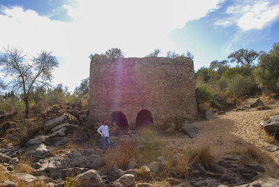 Rear view of women on rock by trees against sky