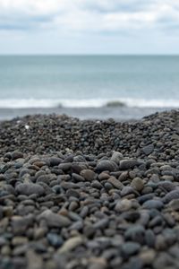 Surface level of stones on beach against sky