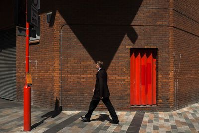 Full length of man walking on footpath against building