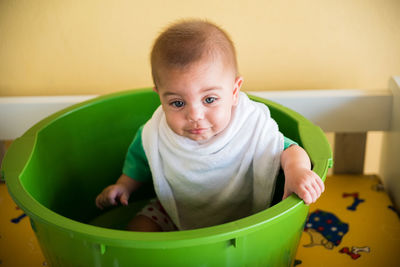 Close-up cute baby boy sitting in bucket at home