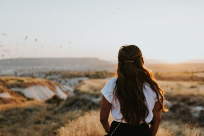 Rear view of woman standing on land against sky