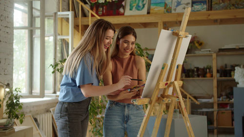 Lesbian couple painting on canvas