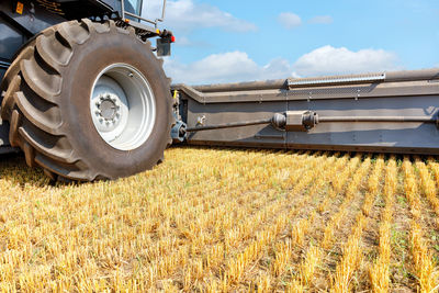 A huge wheel of a combine harvester with a harvesting mechanism against the background of stubble 