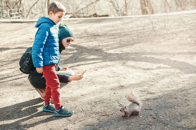 Mother and son taking picture photo of squirrel in park. mom and kid snapping photos of wild animal 
