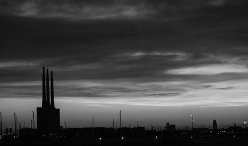 Silhouette of city against cloudy sky