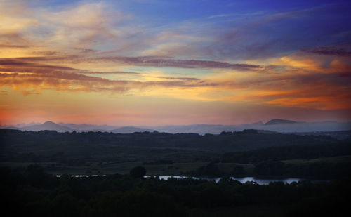 Scenic view of silhouette landscape against orange sky