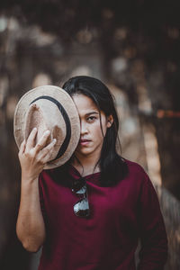 Portrait of young woman holding hat