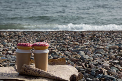 Cup of coffee and donuts on beach