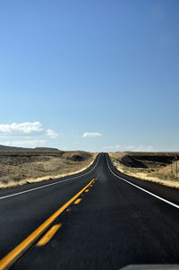 Road amidst landscape against clear blue sky