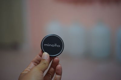 Cropped image of person holding lens cap outdoors