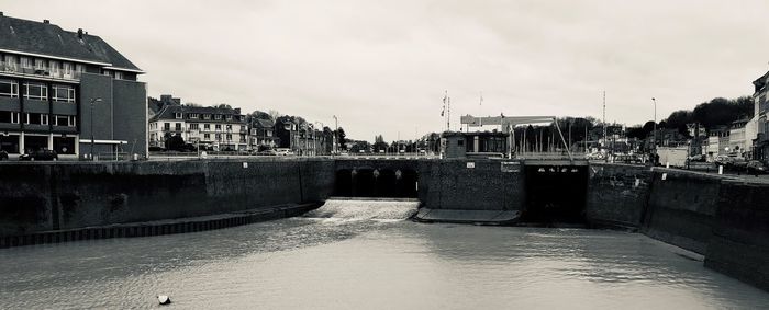 Bridge over river amidst buildings against sky