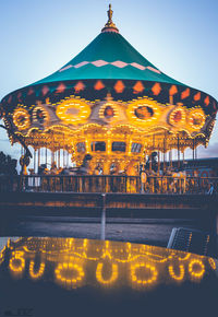 Illuminated carousel against clear sky at night