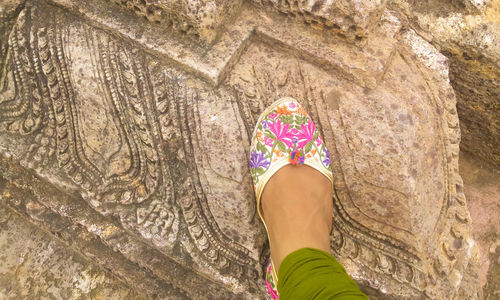 Low section of woman standing on beautiful ancient carved rock