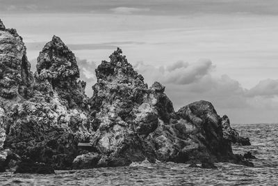 Scenic view of rocks by sea against sky