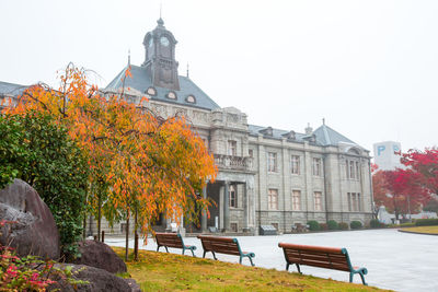 Park by buildings against sky during autumn