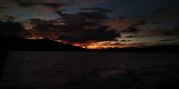 Scenic view of sea against dramatic sky during sunset