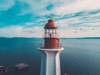 Lighthouse by sea against sky