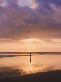 Silhouette person on beach against sky during sunset