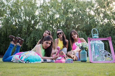 Group of people sitting on grassland against trees