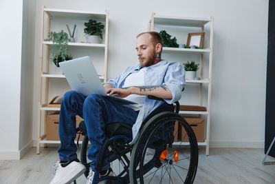 Low section of woman using digital tablet while sitting on wheelchair
