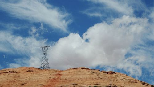 Low angle view of electricity pylon on mountain against sky