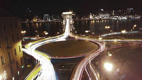Light trails on illuminated city against sky at night
