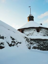 House on snow covered mountain against sky