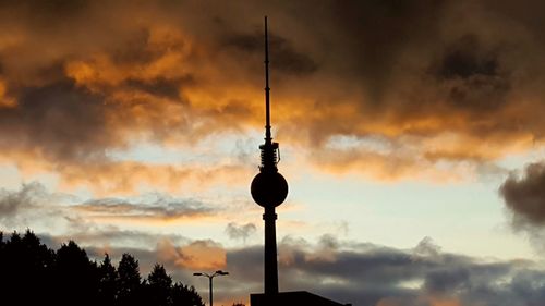 Low angle view of communications tower against cloudy sky