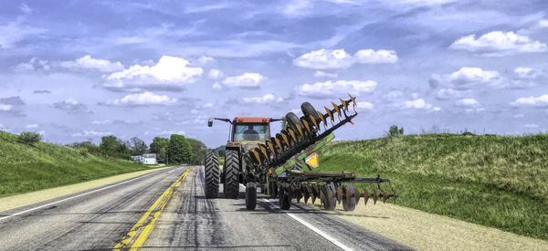 Road amidst field against sky