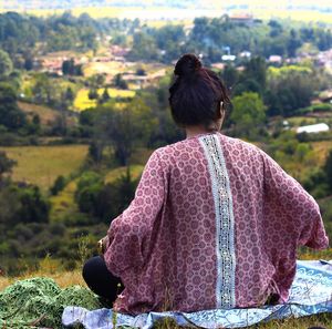 Rear view of woman sitting on hill