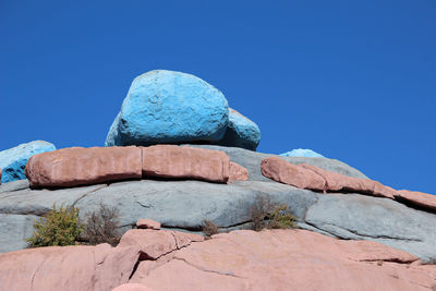 Low angle view of rock formation against clear blue sky