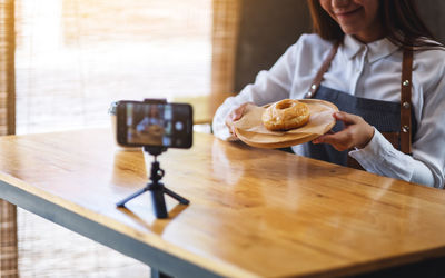 Midsection of woman holding smart phone in restaurant