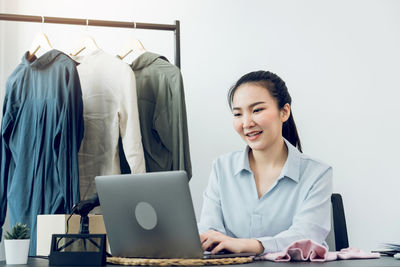 Smiling young woman using phone while sitting on table