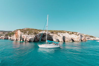 Sailboat sailing on sea against clear blue sky