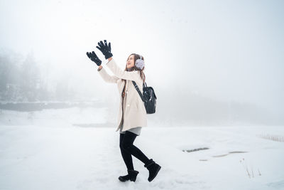 Full length of young woman standing in snow