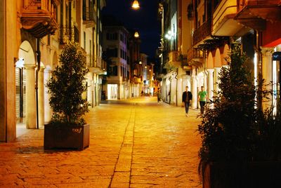 Illuminated street amidst buildings at night