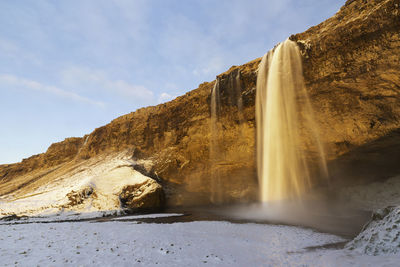 Scenic view of waterfall against sky