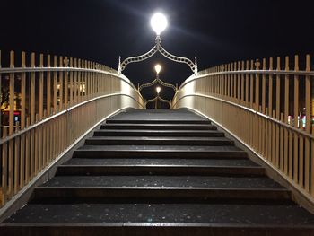 Illuminated footbridge against sky at night