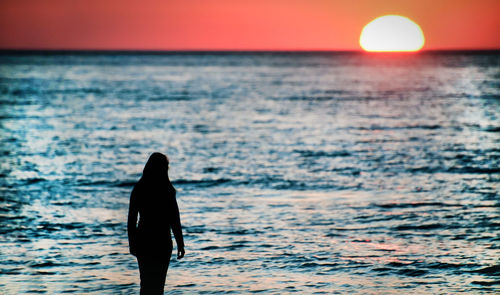 Silhouette man standing on beach against sky during sunset