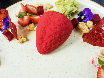 Strawberry shaped almond sponge cake with fruits in plate on table