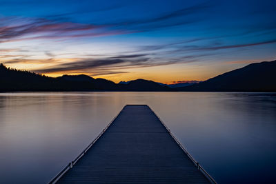 Pier over lake against sky during sunset