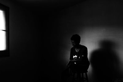 Boy sitting on stool in darkroom