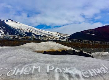 Text on snow covered mountain against sky