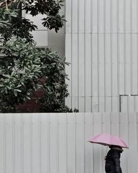 Woman standing by tree against building